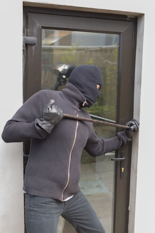 burglar with crowbar prying open a door